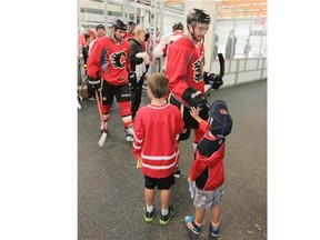 Benett Miller, 8 and his brother Nolan, 4 get some high five’s from players at the Calgary Flames 2014 training camp at the WinSport arenas on Friday.