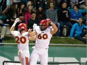 Calgary Dinos running back Mercer Timmis, left and Sean McEwen celebrate a touchdown by Timmis against the University of Saskatchewan Huskies on Friday in Saskatoon.