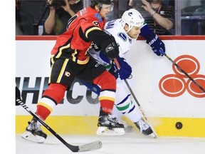 Calgary Flames defenceman Kris Russell and Canucks forward Zack Kassian crash along the boards during the second period of the Calgary Flames’ regular season home opener against the Vancouver Canucks.