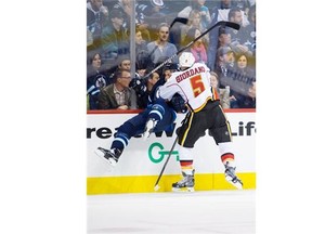 Calgary Flames Mark Giordano (5) checks Winnipeg Jets Michael Frolik (67) into the boards during second period NHL pre-season action in Winnipeg, Saturday October 4, 2014. THE CANADIAN PRESS/David Lipnowski