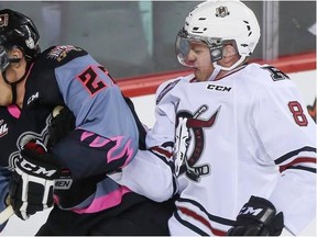 Calgary Hitmen Linden Penner, left, battles off Red Deer Rebel Kayle Doetzel during the Hitmen's home opener against the Red Deer Rebels in Calgary, on September 20, 2014.