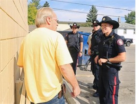 Calgary Police Service constables, from left, Steve Mackenzie, Brad Bliek and Ray Hostland chat with Forest Lawn resident Larry Christman while on foot patrol in Forest Lawn on Wednesday.