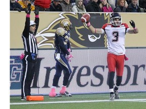 Calgary Stampeders receiver Brad Sinopoli raises his arms in reaction to his touchdown as Maurice Leggett of the Winnipeg Blue Bombers walks behind him on Saturday. A few plays later, Sinopoli left the field to see a trainer where it was determined he had a broken collarbone.