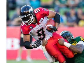 Calgary Stampeders running back Jon Cornish is dragged down by Edmonton’s Willie Jefferson on Saturday. Cornish chugged through the Eskies defence and was a big reason the Stamps won.