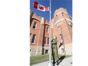 Capt. Steven Zivkow, regular force support officer to the Highlanders, re-enacts the lowering of the flag at Mewata Armoury in honour of the slain Canadian soldiers in Ottawa and Quebec, on Thursday, Oct. 23, 2014.