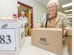 Caren Best, right, supervisory deputy returning officer, is given her supply box by Ed Kuntz, administrative assistant at the Calgary-Elbow returning office, as everyone gets prepared for Monday’s byelection.