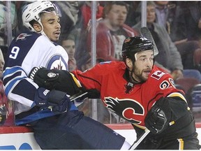 Derek Engelland of the Calgary Flames slams Kane Evander of the Winnipeg Jets into the glass during a game earlier this month. Engelland expressed concern for ex-Pittsburgh Penguins teammate Olli Maatta, who is getting a tumour removed next week, which has an 85% chance of being low-grade thyroid cancer.