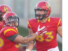 Dinos receiver Brendan Thera-Plamondon, right, celebrates his first quarter touchdown against the Manitoba Bisons with running back Bryce Harper. The Dinos came back to win 42-41.