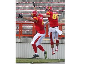 Dinos receiver Brett Blaszko, right, celebrates with teammate Jake Harty after a touchdown last week against the Manitoba Bisons at McMahon Stadium.