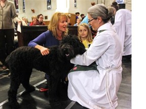 Doris and Janaea Koffman receive a blessing for their pooch from the Reverend Natasha Brubaker Garrison at the 17th annual Blessing of the Animals at the Cathedral Church of the Redeemer in Calgary last year.