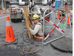 Enmax lineman Marshall Sofa descends into the infamous manhole on 8th Street S.W. on Wednesday to replace cable burned by this past weekend’s fire.