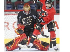 Flames goalie Jonas Hiller stops a deflection by teammate Paul Byron during practice at the Saddledome on Wednesday. The Swiss netminder was buoyed by being named Calgary’s starter for the forseeable future.