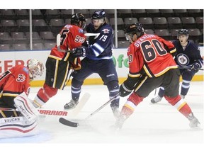 Flames goalie Joni Ortio covers up as defenceman John Ramage, 55, and centre Markus Granland tie up Winnipeg Jets attacker Nikolas Broulliard during the first period of Friday’s win at the Young Stars Classic in Penticton, B.C.