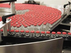 Bottles of flu vaccine rotate on a plate as they make their way through a GlaxoSmithKline assembly line on Dec. 9, 2004 in in Ste. Foy, Que. THE CANADIAN PRESS/Jacques Boissinot