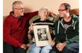 Helen Salus, along with son John and grandson Jesse, holds a photo of herself and her husband John on their wedding day.