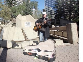 Johnny Chase plays his guitar in front of Century Gardens at 8th Street and 8th Avenue SW Thursday October 2, 2014. The controversial downtown park with its brutalist architecture will be undergoing a refurbishing.