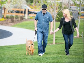 Michelle Hofer/For the Calgary Herald Joe Swain and Brook Baxendale go for a walk with their dog Yota at a park in the Cochrane community of Fireside recently.