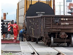 Crews work to lift two CN railway cars that derailed  at a crossing over 52nd Street S.E. just south of 50th avenue on Tuesday morning. Traffic was blocked both north and southbound while the cars were lifted by a large crane back onto the tracks.