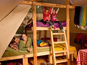 Family in bunk beds enjoying camping experience inside oTENTik tent, Rivière à la Pêche campground.  /  Une famille s'amuse en camping sur des lits superposés à l'intérieur d'une tente oTENTik, camping de Rivière à la Pêche.
