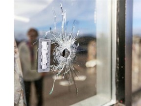 A passerby looks at the bullet holes following an overnight shooting that left shattered windows at Mr. Schnapps Pub on the 1400 block of 52nd Street N.E. in Calgary, on October 6, 2014.