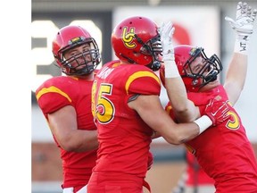 Quentin Chown, right, celebrates a touchdown with teammates after the Dinos whipped the U of A Golden Bears 71-3. Unfortunately, the game will now go into the record books as a 1-0 win for the U of A after two Dinos players were ruled academically ineligible. The school is not naming the players.