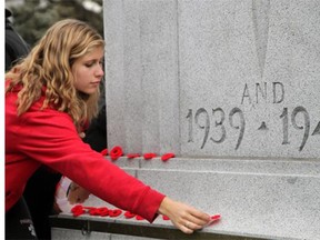 A woman places her poppy on the cenotaph in Calgary during 2011 Remembrance Day services. Reader says people should support veterans every year buy buying a new poppy.