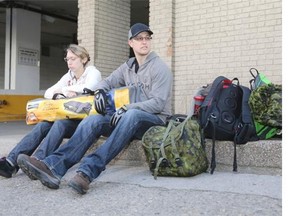 Sarah Borushynski and Matthew Frantz wait for a ride with a few of their possessions. Their apartment and many adjacent  buildings in downtown Calgary are without power.