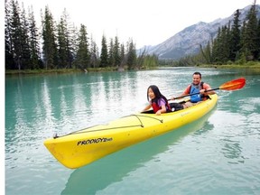 Mia Scovnaienchi, 8, and her dad, Luigi, paddle the Bow River from The Banff Canoe Club dock. Banff National Park recorded a 15 per cent increase through the end of July in the number of visitors compared with last year.