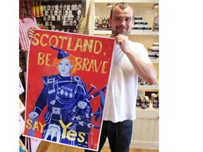 Shop owner Stewart Cattanach holds up posters he´s been printing from inside his Tobermory handmade soap shop. Cattanach says he supports secession to ensure Scotland remains integrated into the European Union. (Courtesy, Jacob Resneck/Calgary Herald)