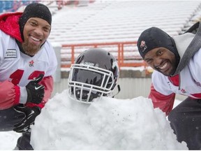 Stampeders Juwan Simpson, and Keon Raymond pose after putting a helmet on the remains of ‘Snow Levi Mitchell’ — the snowman players created and DeVone Claybrooks destroyed during practice at McMahon Stadium on Wednesday.