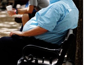 In this Thursday, Sept. 4, 2014, file photo, an overweight man rests on a bench in Jackson, Miss. Research shows obese men earn less and face mounting health issues as they age.