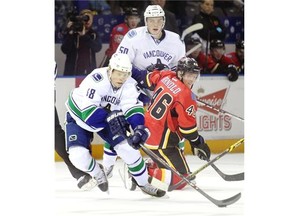 Vancouver Canucks prospect Hunter Shinkaruk of Calgary lunges away from Calgary Flames prospect Bill Arnold while teammate Brendan Gaunce looks on during the second period of their match at the Youngstars Tournament in Penticton, B.C. on Monday.