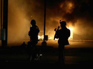 Police officers in riot gear stand in front of a burning building during a protest on November 24, 2014 in Ferguson, Missouri. A St. Louis County grand jury has decided to not indict Ferguson police Officer Darren Wilson in the shooting of Michael Brown that sparked riots in Ferguson, Missouri in August.