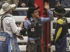 Edgar Durazo, bull rider from Mexico, high-fives the rodeo clowns after his winning bull ride at the World Professional Bull Riding championship