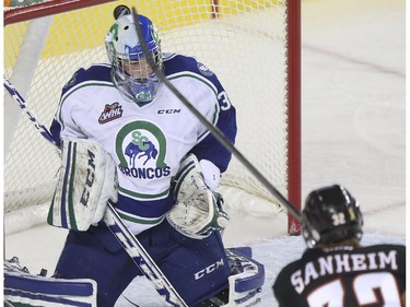 Calgary Hitmen Travin Sanheim sneaks one past Swift Current Broncos goalie Landon Bow during Western Hockey League action at the Scotiabank Saddledome in Calgary, on November 28, 2014.