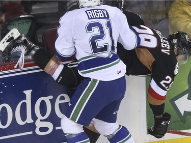 Calgary Hitmen Radel Fazleev takes a hit from Swift Current Bronco Carter Rigby during Western Hockey League action at the Scotiabank Saddledome in Calgary, on November 28, 2014.