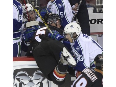 Calgary Hitmen Keegan Kanzig takes a hit into the Swift Current Broncos bench from Cavin Leth during Western Hockey League action at the Scotiabank Saddledome in Calgary, on November 28, 2014.