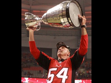The Calgary Stampeders head coach John Hufnagel holds the Grey Cup while wearing John Forzani's old jersey after the team won the 2014 Grey Cup in Vancouver on Sunday November 30, 2014.