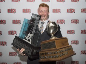 Andrew Buckley, from the University of Calgary, holds up his Russ Jackson Centaur trophy, left, and trophy for most outstanding player of the year during the CIS football awards ceremony in Montreal, Thursday, November 27, 2014.