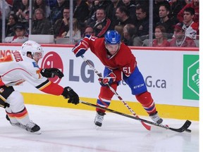 T.J. Brodie of the Calgary Flames pokes the puck away from David Desharnais of the Montreal Canadiens during Sunday’s game.