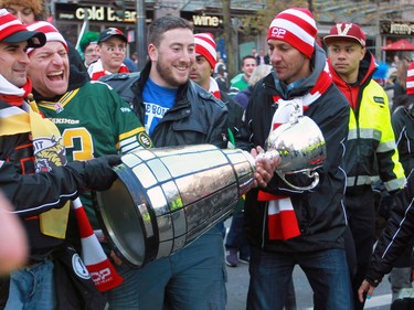 Football fans take turns carrying the Grey Cup towards B.C. Place in the fan march before the 2014 Grey Cup in Vancouver on Sunday November 30, 2014.