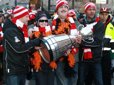 Football fans take turns carrying the Grey Cup towards B.C. Place in the fan march before the 2014 Grey Cup in Vancouver on Sunday November 30, 2014.