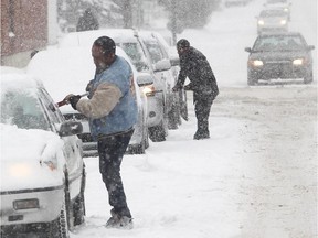 Drivers clear snow off the vehicles on 20th Avenue NE at Centre Street on November 9, 2014. Albertans can expect a winter of extremes again this year.