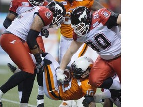 Calgary Stampeders’ Juwan Simpson, left, and Quinn Smith, right, tackle B.C. Lions’ Stefan Logan during Friday’s game in Vancouver. The Stamps cruised to a 33-16 win to finish the season with a 15-3 record.
