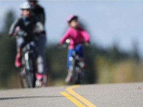 Cyclists ride by double lines painted on Sept. 28 along the pathway system near the Calgary Sailing Club.