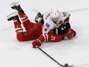 Calgary Flames' Kris Russell (4) and Carolina Hurricanes' Chris Terry (25) fall to the ice chasing the puck during the third period of an NHL hockey game in Raleigh, N.C., Monday, Nov. 10, 2014.