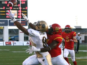 The Calgary Dinos' Cyril Iwanegbe, right, tries to block a pass to Manitoba Bisons receiver Nic Demski at McMahon Stadium on September 20, 2013.