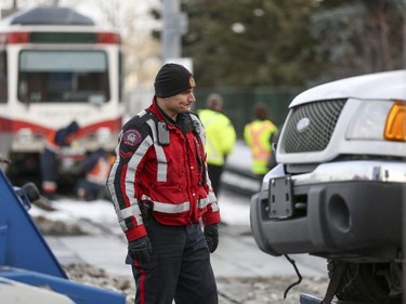 A Calgary police officer surveys the damage done to a truck hit by the C-train when it crossed the track at the intersection of 9 Street SW and 4 Avenue SW in Calgary, on November 20, 2014.