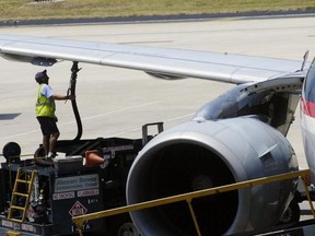 A worker hooks up a fuel hose to an airplane at Tampa International Airport.