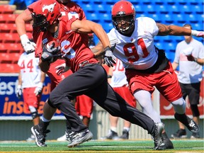 Gavin Young, Calgary Herald CALGARY, AB: JULY 10, 2014 --     Calgary Stampeders defensive lineman Evans DeQuin, right, reaches out for wide receiver Anthony Parker during a drill at practise at McMahon Stadium on Thursday July 10, 2014. The team heads to Toronto for Saturday's game. Gavin Young/Calgary Herald  (For Sports section story by TBA) Trax# 00057106A